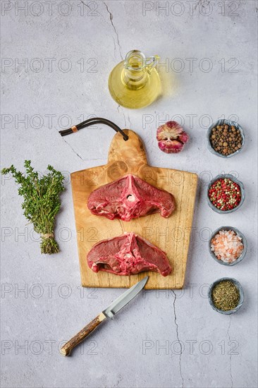 Overhead view of raw fresh deer backstrap with spice and herb over concrete background