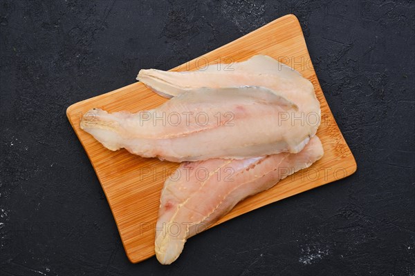 Top view of raw fresh haddock fillet on wooden cutting board