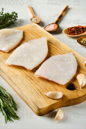 Raw frozen squid fillet on wooden cutting board