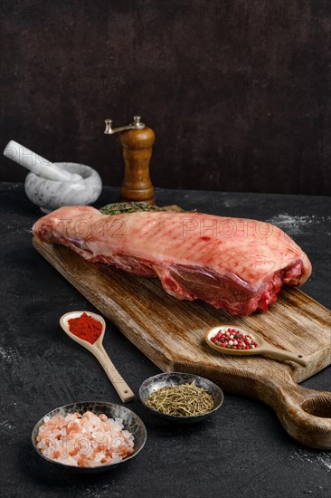 Raw half of turkey breast with bone and skin on dark background