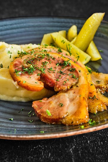 Close up view of baked bacon with mashed potato and pickle cucumber