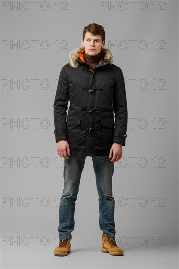 Full length portrait of handsome man in warm winter coat posing in studio