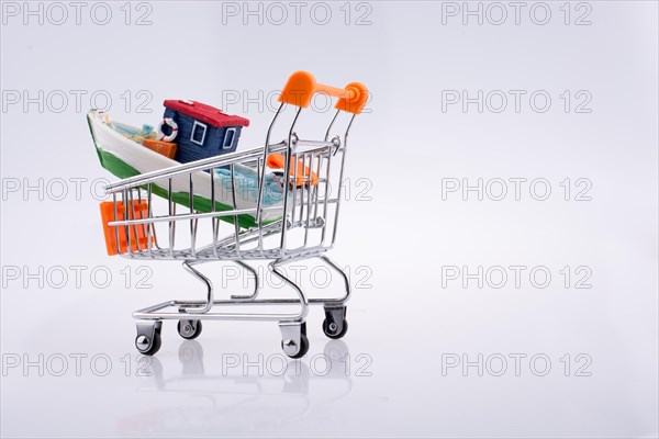 Little colorful model boat in shopping cart on white background