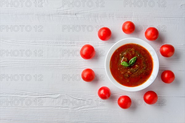 Top view of wooden table with plate with gazpacho and tomato cherry