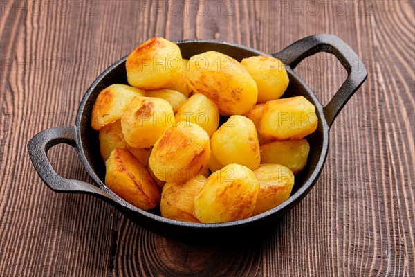 Baked potato in cast iron skillet on natural wooden background