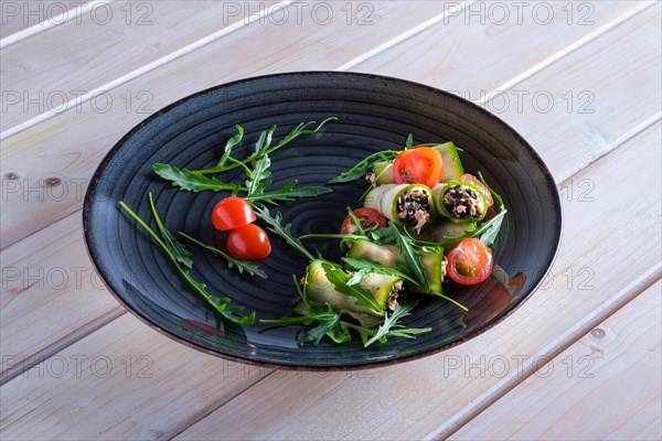 Chopped smoked salmon and black olives rolled in cucumber decorated with tomato and arugula