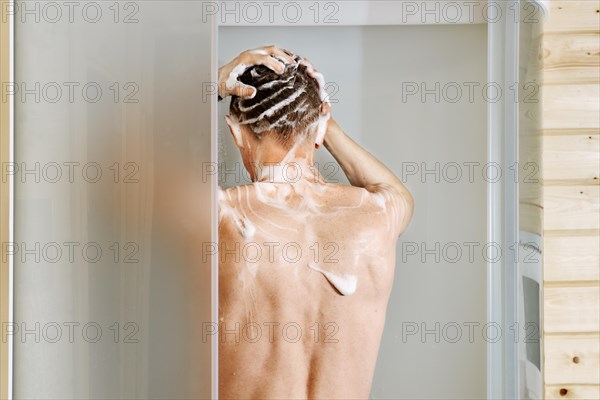 Back view of a man washing hair in the shower