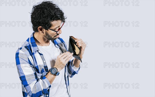 Man with financial problems showing empty wallet. Moneyless frustrated person concept. Sad man shaking an empty wallet