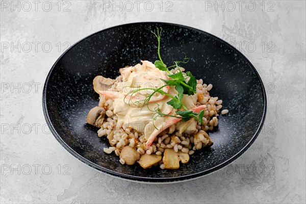 Boilet pearl barley with fried mushrooms and creamy flour sauce on a plate