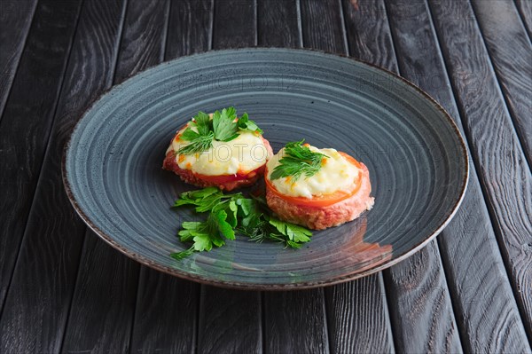 Appetizer for reception. Fish cutlet with slice of tomato and melted cheese