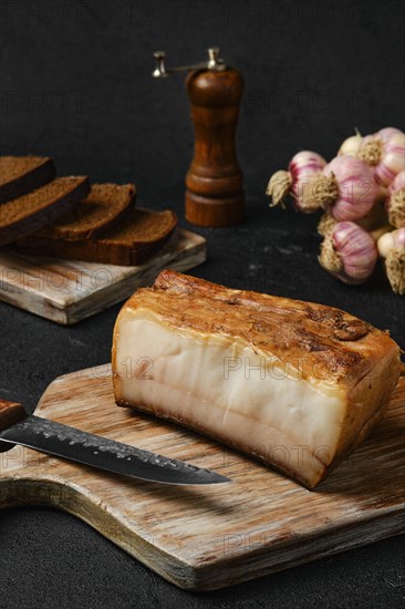 Smoked fat with brown bread on wooden cutting board