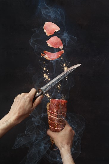 Male hand with knife cutting smoked beef ham