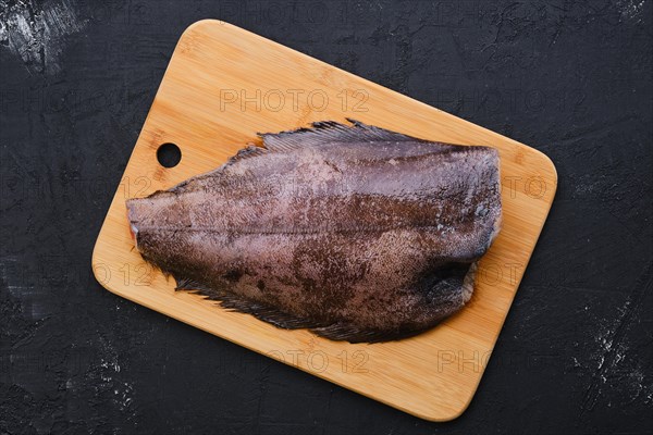 Top view of raw fresh halibut without head on wooden cutting board