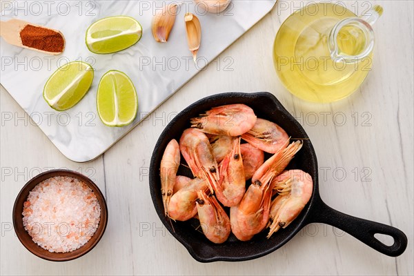 Top view of cast iron skillet with steamed unpeeled shrimps with spice