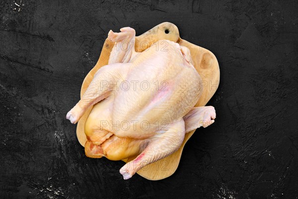 Fresh raw whole farm chicken on wooden cutting board