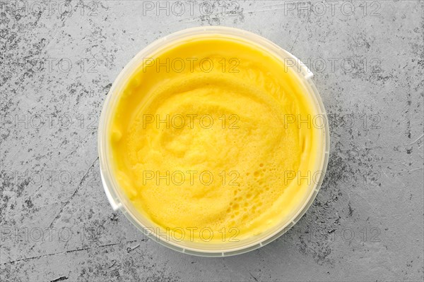 Top view of homemade cream cheese in plastic bowl