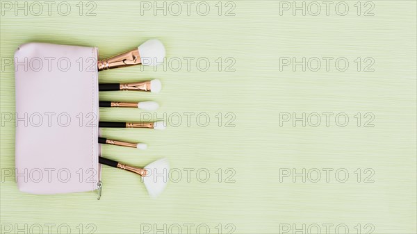 Makeup brushes inside open bag mint green background