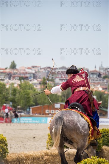 Archer with bow in traditional clothes shooting an arrow