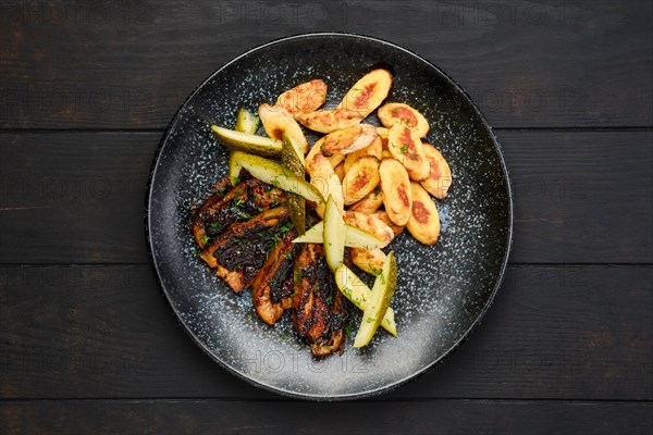 Overhead view of roasted pork belly slices with pickled cucumber and gnocchi