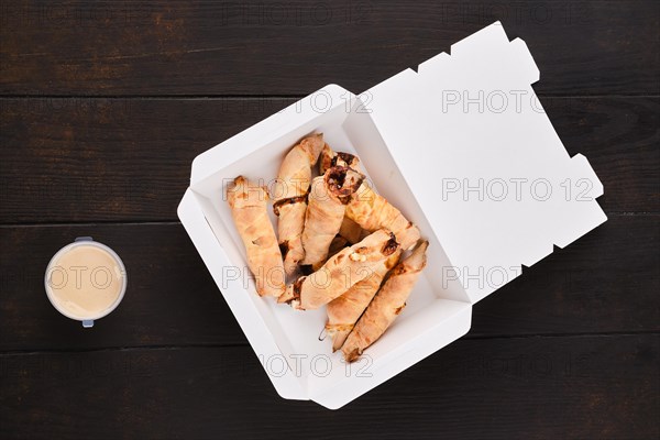 Slices of pear rolled in dough with caramel sauce in take away cardboard box