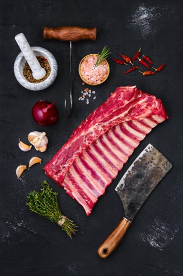 Fresh raw rack of lamb on wooden cutting board with herbs and seasoning