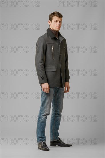 Full length portrait of handsome man in warm woolen coat posing in studio