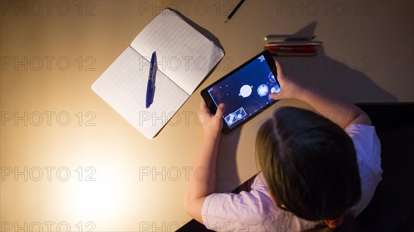 Girl playing tablet game evening