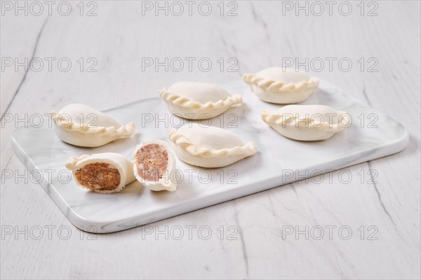 Frozen dumplings stuffed with beef meat and provencal herbs on marble serving plate