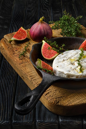 Closeup view of camembert cheese and figs ready for baking on frying pan