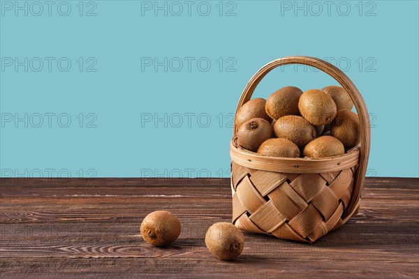 Basket with fresh kiwi on wooden table