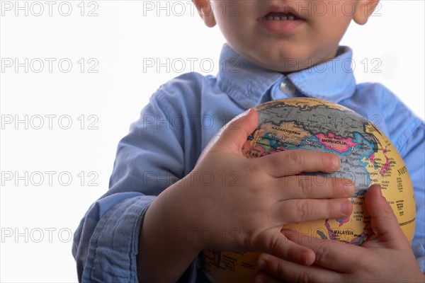 Baby with blue shirt holding a globe in hand on white background