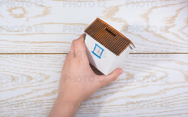 Little model housein hand on a parquet background