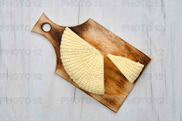 Fresh Adyghe cheese cut on slices on wooden cutting board