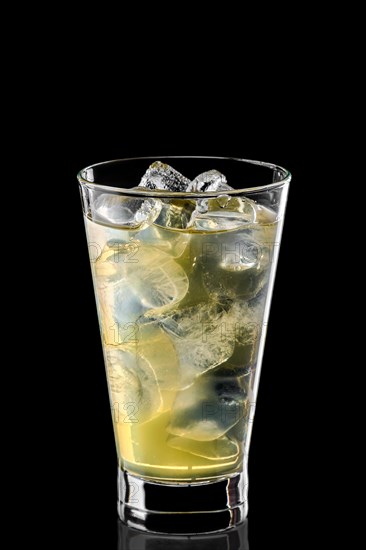Glass of cold water with ice cubes and pear syrup isolated on black background