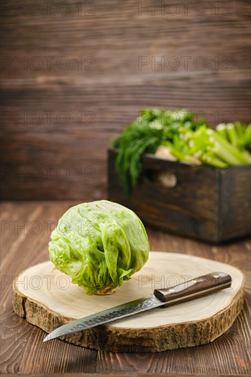 Fresh whole iceberg lettuce on wooden cutting board