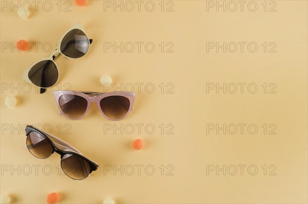 Different types sunglasses with pom pom beige backdrop
