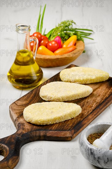 Semifinished homemade zander cutlet on a wooden serving board