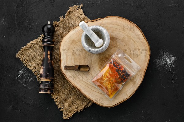 Wooden cross section with a set of spices for pilaf in plastic package and stone mortar and mill