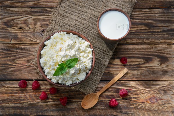 Cottage cheese and milk in clayware on wooden table