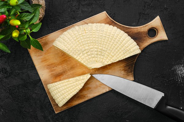 Fresh Adyghe cheese cut on slices on wooden cutting board