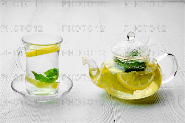 Antioxidant hot drink with lemon and mint in transparent tea pot and glass