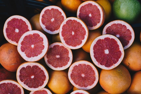 Cut in halves grapfruits alongside pomegranates on display