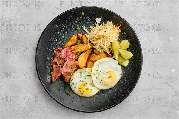 Top view of two fried eggs with bacon and pickled cabbage with cucumber