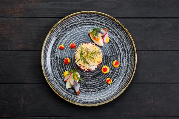 Top view of herring layered salad decorated with a quarter of a boiled egg and a piece of herring