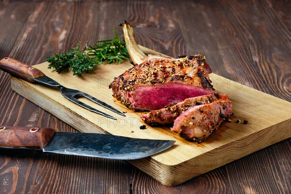 Medium rare cowboy steak on wooden cutting board