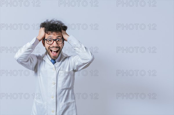 A mad scientist pulling his hair out on isolated background. Mad scientist grabbing his hair with a mad face isolated. A doctor with a crazy face looking at the camera