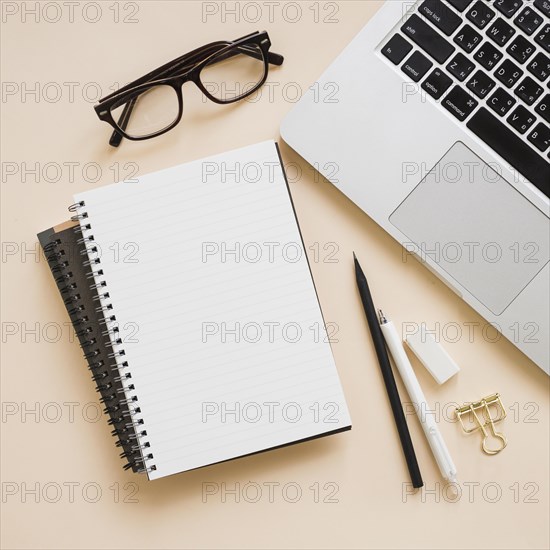 Overhead view stationeries laptop beige background