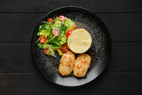 Top view of meat cutlet with mashed potato and fresh vegetables on a plate