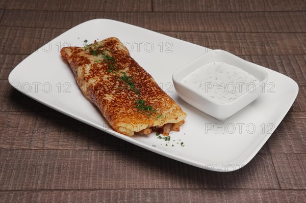 Traditional russian pancake with ham and sauce