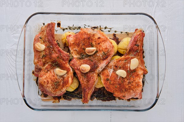 Steak with bone and potato baked in oven in a roasting pan with garlic and thyme